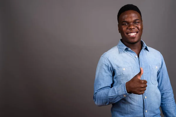 Joven hombre africano con camisa de mezclilla sobre fondo gris —  Fotos de Stock