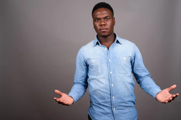 Joven hombre africano con camisa de mezclilla sobre fondo gris — Foto de Stock