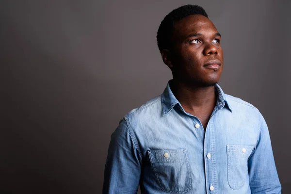 Joven hombre africano con camisa de mezclilla sobre fondo gris — Foto de Stock
