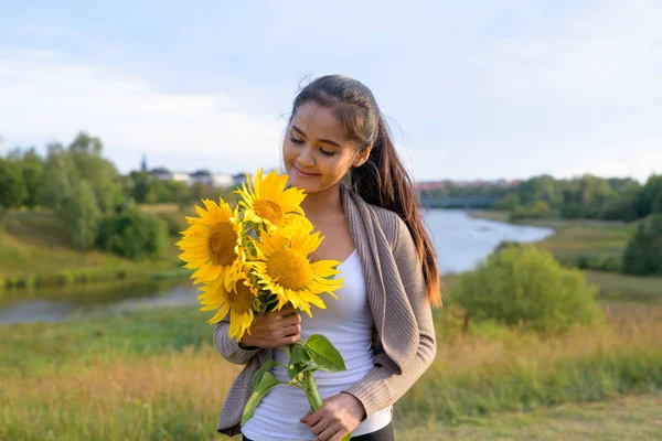 Jeune femme asiatique heureuse avec bouquet de tournesols contre la vue relaxante sur la nature — Photo