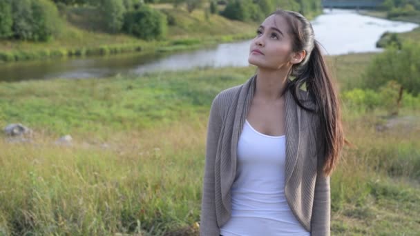 Młody szczęśliwy Asian kobieta myśli przeciwko relaksujący widok natury — Wideo stockowe