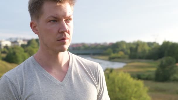 Head shot of young happy handsome man thinking against beautiful relaxing view of nature — Stock Video