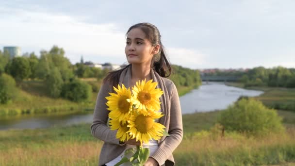 Νέοι ευτυχισμένη γυναίκα της Ασίας σκέψης ενώ προβάλετε εκμετάλλευση ηλιοτρόπια κατά της χαλάρωσης της φύσης — Αρχείο Βίντεο