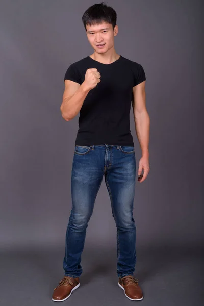 Studio shot of young Chinese man against gray background — Stock Photo, Image