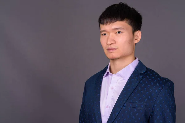 Portrait of young Chinese businessman against gray background