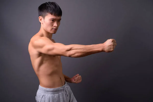 Ung skjorta kinesiska mannen mot grå bakgrund — Stockfoto