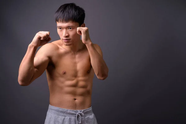 Joven chino sin camisa contra fondo gris — Foto de Stock