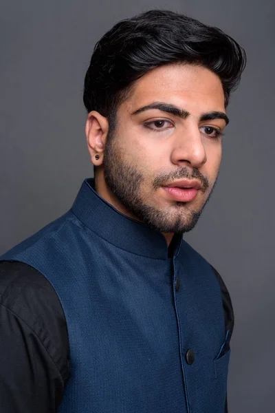 Fiatal jóképű indiai üzletember szürke háttérrel — Stock Fotó