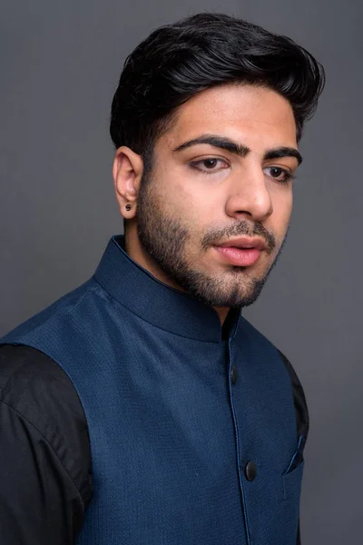 Young handsome Indian businessman against gray background — Stock Photo, Image