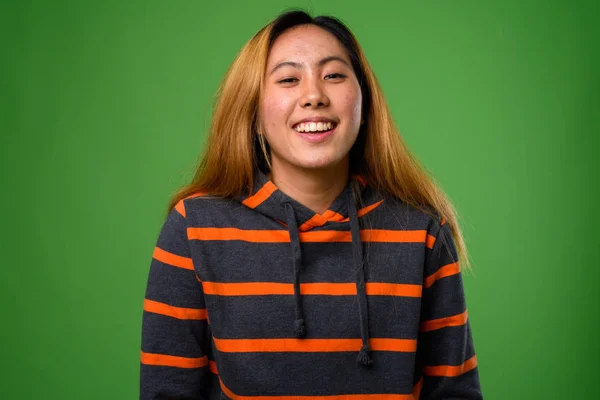 Portrait of young Asian woman against green background — Stock Photo, Image