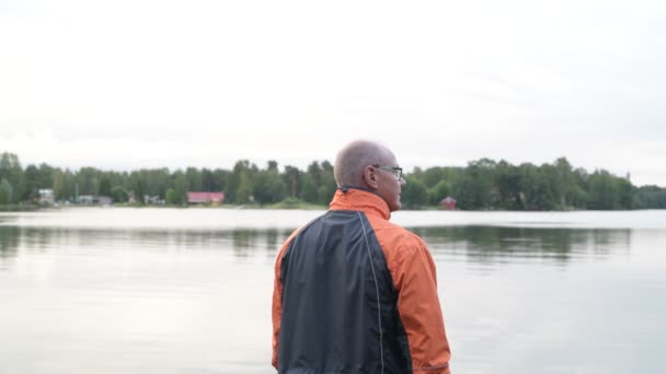Bakifrån av äldre Man njuter av utsikten över sjön — Stockvideo