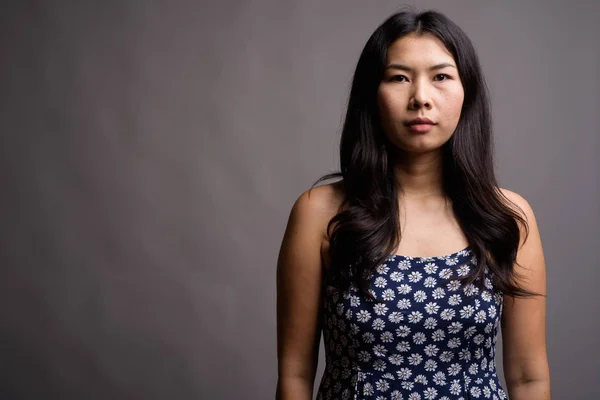 Mujer asiática vistiendo vestido azul contra fondo gris —  Fotos de Stock