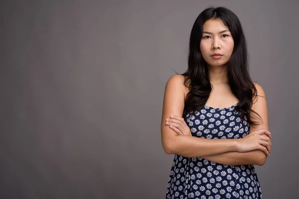 Mujer asiática vistiendo vestido azul contra fondo gris —  Fotos de Stock