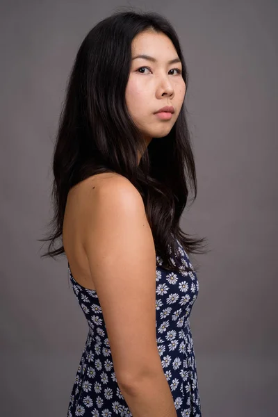 Asiatisk kvinna bär blå klänning mot grå bakgrund — Stockfoto