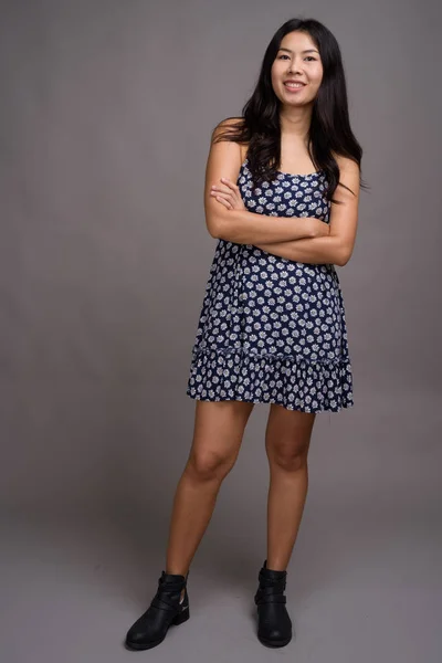 Mujer asiática vistiendo vestido azul contra fondo gris —  Fotos de Stock