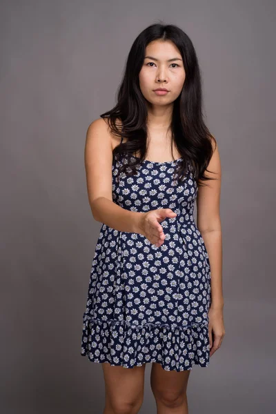 Mujer asiática vistiendo vestido azul contra fondo gris —  Fotos de Stock