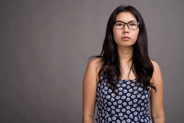 Mujer asiática usando anteojos contra fondo gris —  Fotos de Stock