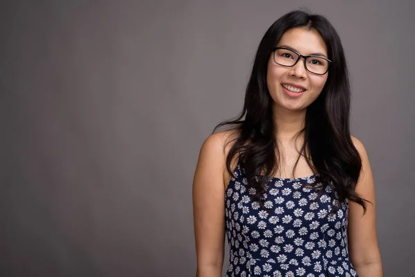 Asiatisk kvinna bär glasögon mot grå bakgrund — Stockfoto