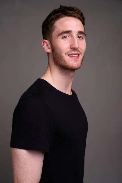 Portrait of young handsome man against gray background — Stock Photo, Image