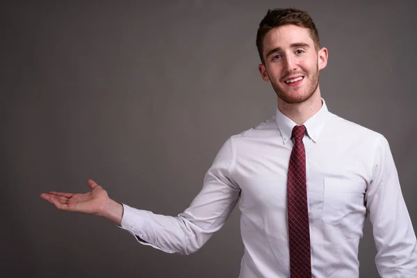 Porträt eines jungen, gut aussehenden Geschäftsmannes vor grauem Hintergrund — Stockfoto