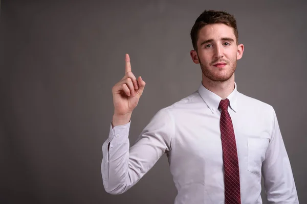 Retrato de jovem empresário bonito contra fundo cinza — Fotografia de Stock