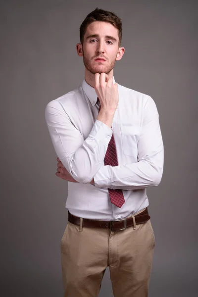 Retrato de jovem empresário bonito contra fundo cinza — Fotografia de Stock