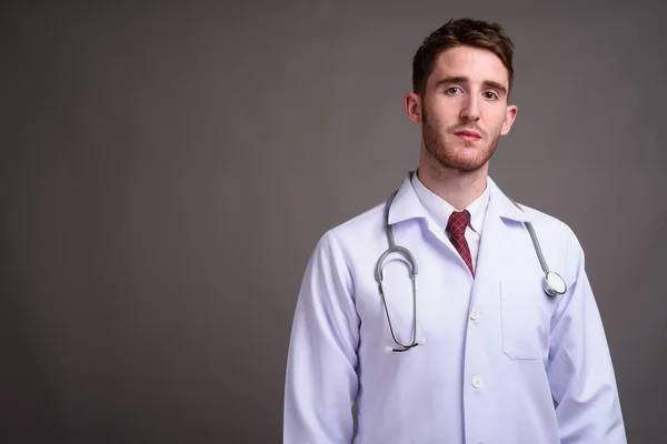 Giovane bello uomo medico contro sfondo grigio — Foto Stock