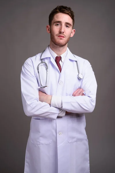 Joven hombre guapo médico contra fondo gris —  Fotos de Stock