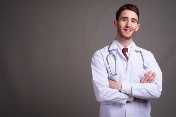 Jovem bonito homem médico contra fundo cinza — Fotografia de Stock