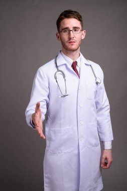Genç yakışıklı Doktor gri backgr karşı gözlük takan adam