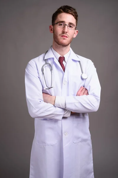 Joven hombre guapo médico con anteojos contra gris backgr —  Fotos de Stock
