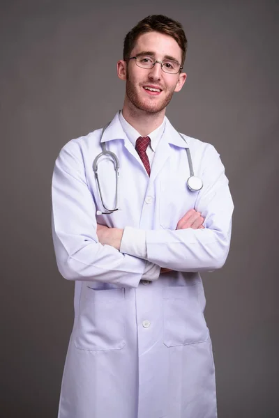 Joven hombre guapo médico con anteojos contra gris backgr — Foto de Stock