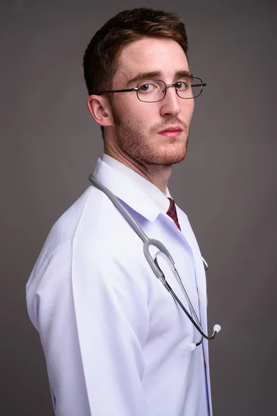 Młody, przystojny lekarz noszenia okularów z szarym tle — Zdjęcie stockowe