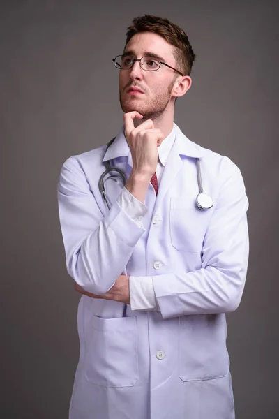 Joven hombre guapo médico con anteojos contra gris backgr — Foto de Stock