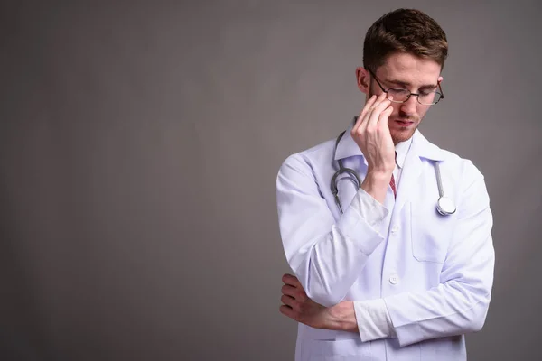 Jeune homme beau médecin portant des lunettes contre backgr gris — Photo