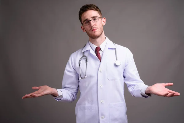 Jeune homme beau médecin portant des lunettes contre backgr gris — Photo