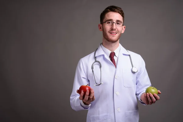 Jeune homme beau médecin portant des lunettes contre backgr gris — Photo