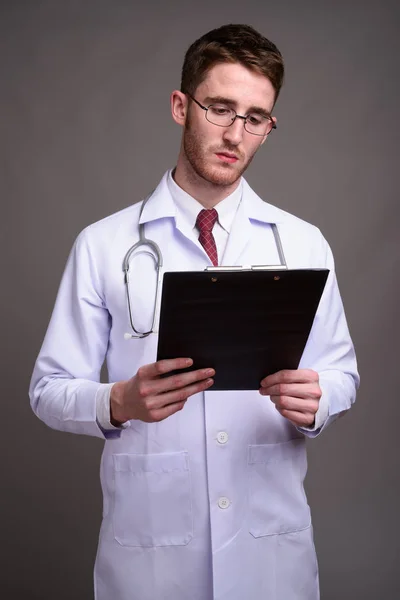 Молодой красивый доктор в очках против серого бэкгра — стоковое фото