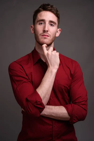 Joven hombre de negocios guapo con camisa roja contra gris backgr — Foto de Stock