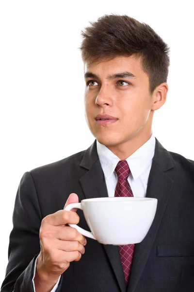 Young handsome businessman holding coffee cup while thinking — Stock Photo, Image