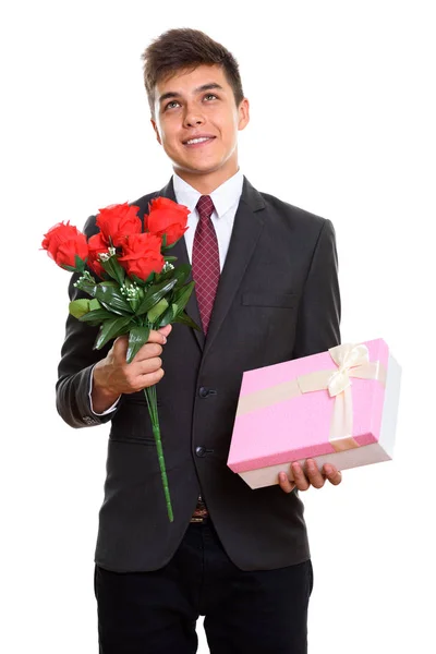 Thoughtful young happy businessman smiling while holding red ros — Stock Photo, Image