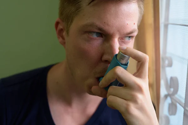 Jeune homme beau utilisant un inhalateur d'asthme à la maison — Photo