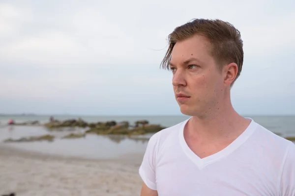Крупный план молодого красивого человека, думающего на общественном пляже H — стоковое фото