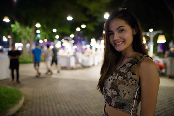 Joven mujer asiática feliz sonriendo contra la vista panorámica de la noche —  Fotos de Stock