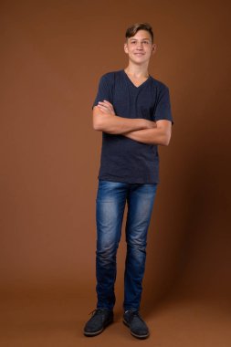 Stüdyo çekim Genç yakışıklı genç çocuk kahverengi backgrou karşı