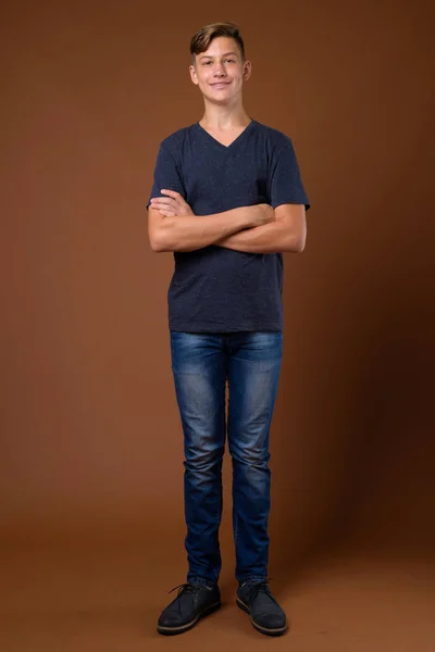 Studio shot of young handsome teenage boy against brown backgrou — Stock Photo, Image
