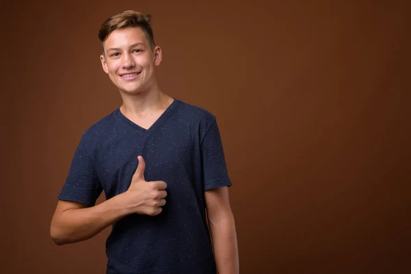 Estúdio tiro de jovem adolescente bonito contra backgrou marrom — Fotografia de Stock