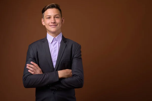 Studio shot of young handsome businessman against brown backgrou — Stock Photo, Image