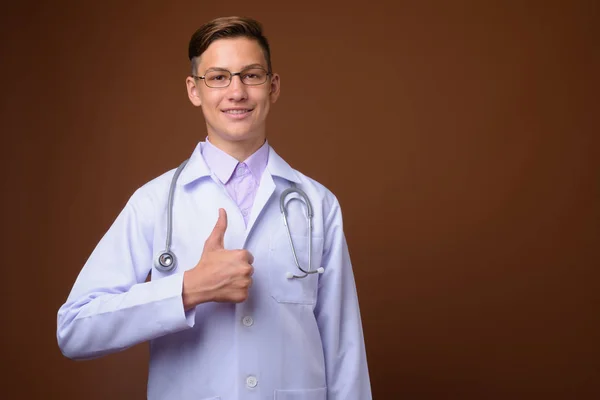 Estúdio tiro de jovem médico bonito contra fundo marrom — Fotografia de Stock