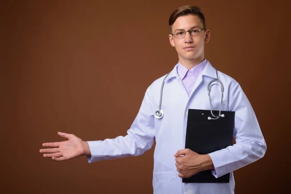 Estudio disparo de joven médico guapo sobre fondo marrón — Foto de Stock